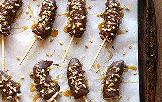 Tray of Chocolate Covered Frozen Bananas with Caramel and Walnuts.