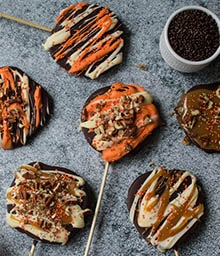 Caramel Apple Pops topped with festive colored frosting and nuts.