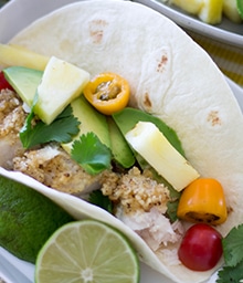 Macadamia Crusted Mahi Mahi Tacos topped with tomatoes, avocados, and pineapples.