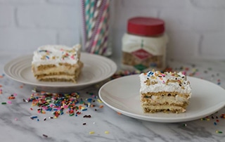 Two slices of No Bake Cake Batter Lasagna topped with sprinkles.