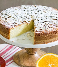 Raised display plate of Orange Almond Cake with slice removed.