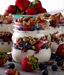 Glass jars of layered Berry Yogurt Breakfast Parfaits.