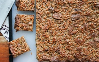 Coconut Pecan Bars yet to be sliced on cutting board.
