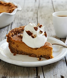 Slice of Pumpkin Mousse Pie with Pecan Nut Crust topped with whipped cream.