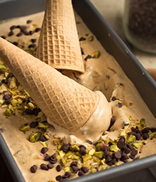 Two cones dipping into pan of Pumpkin Spice Latte Ice Cream.