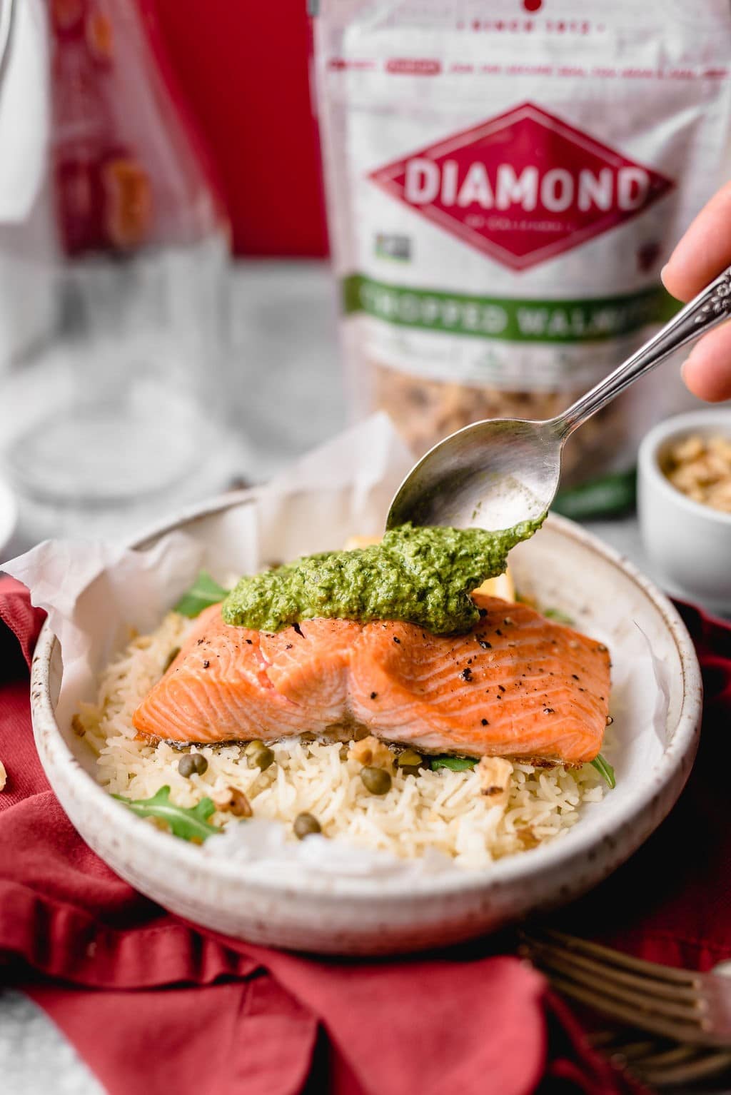 Bowl of rice and Roasted Salmon with Dairy-Free Arugula Walnut Pesto in front of bag of Diamond walnuts.