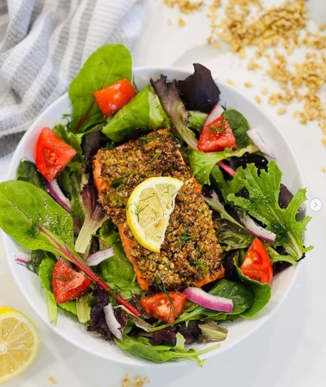 Large green salad topped with Air Fryer Walnut Crusted Salmon.