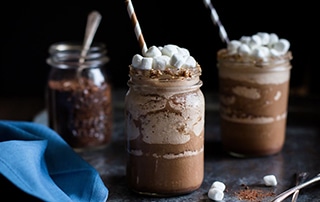 Mason jars with Boozy S'mores Frozen Hot Chocolate topped with marshmallows.