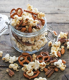 Small jar overflowing with Spiced Popcorn Snack Mix.