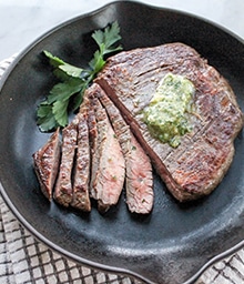 Sliced Steak with Walnut Gremolata Butter in a cast iron pan.