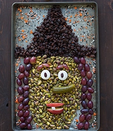 Cartoon witch face made from fruit, veggies, and nuts.